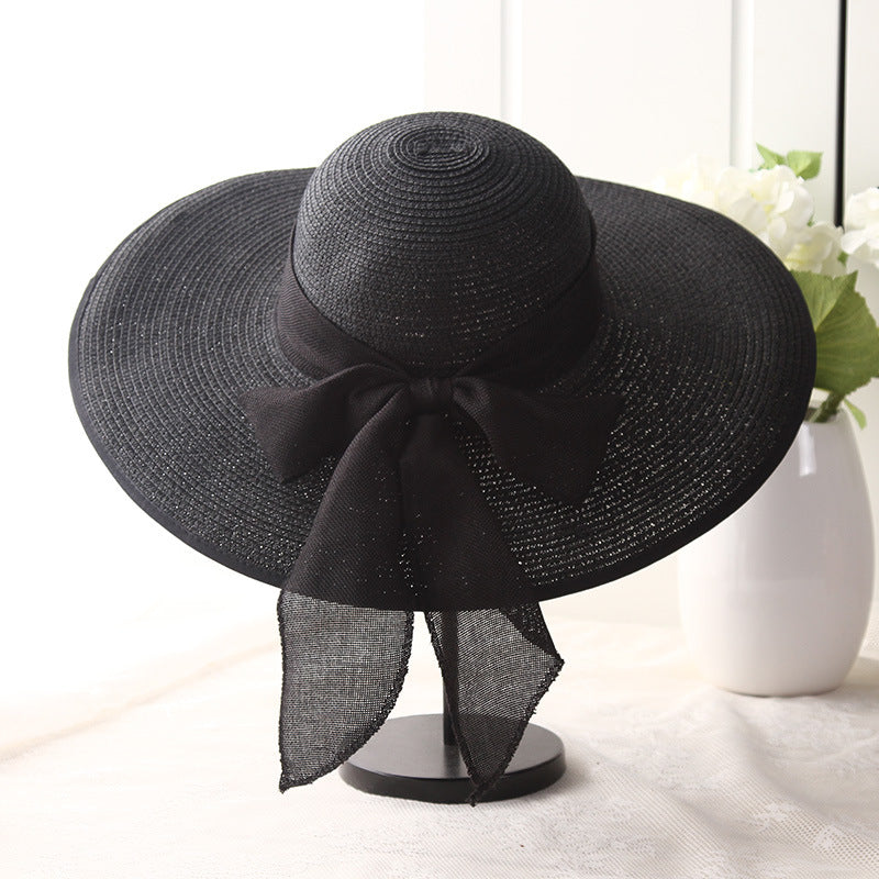 Dark wide-brim straw sun hat with black ribbon bow