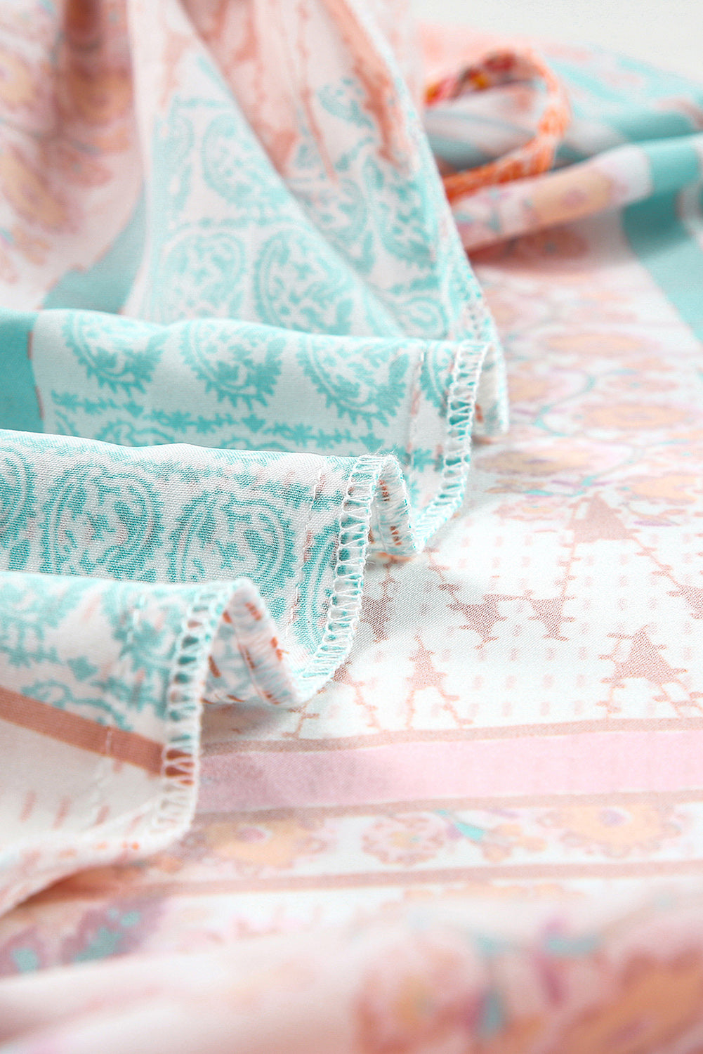 Patchwork sundress sleeve and ruffle hem close-up with teal and peach prints