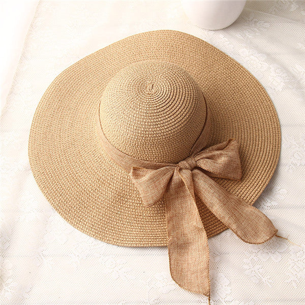 Light brown wide-brim straw sun hat with bow ribbon and spiral texture
