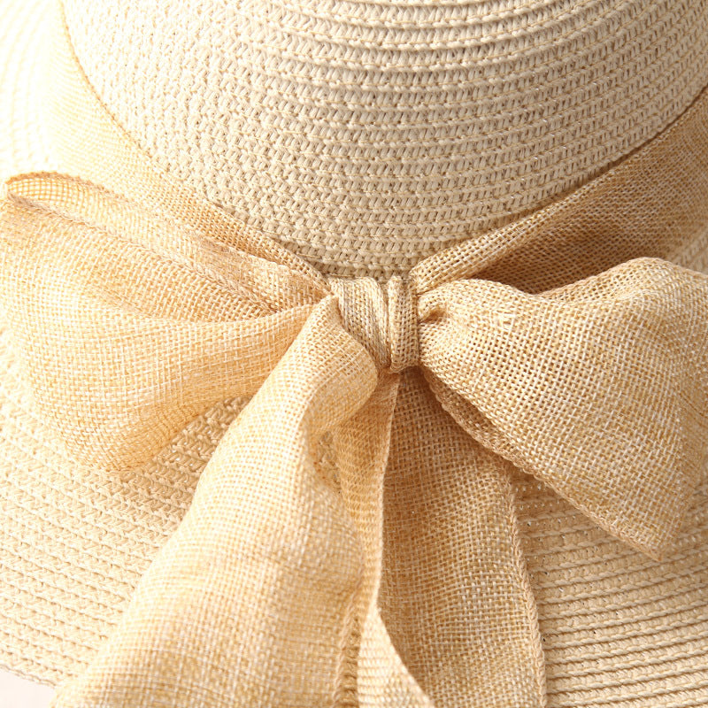 Beige wide-brim straw sun hat with tied fabric ribbon bow