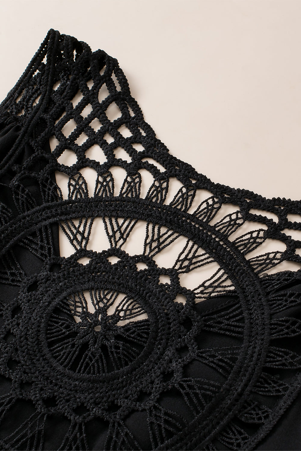 Black crochet yoke panel with circular floral motif on a sleeveless tunic