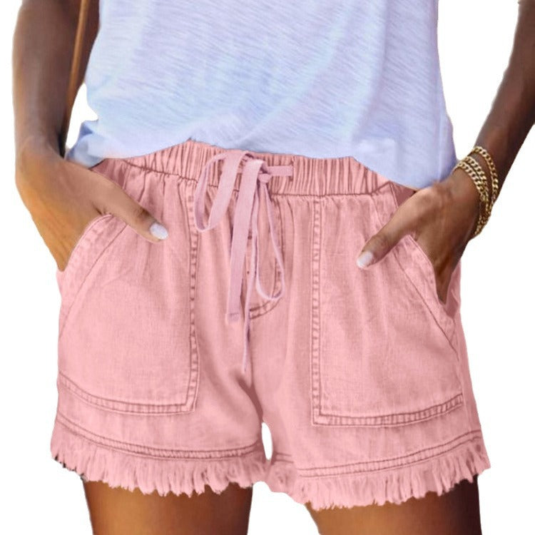 Pink denim shorts with elastic waist, drawstring, and frayed fringe hem