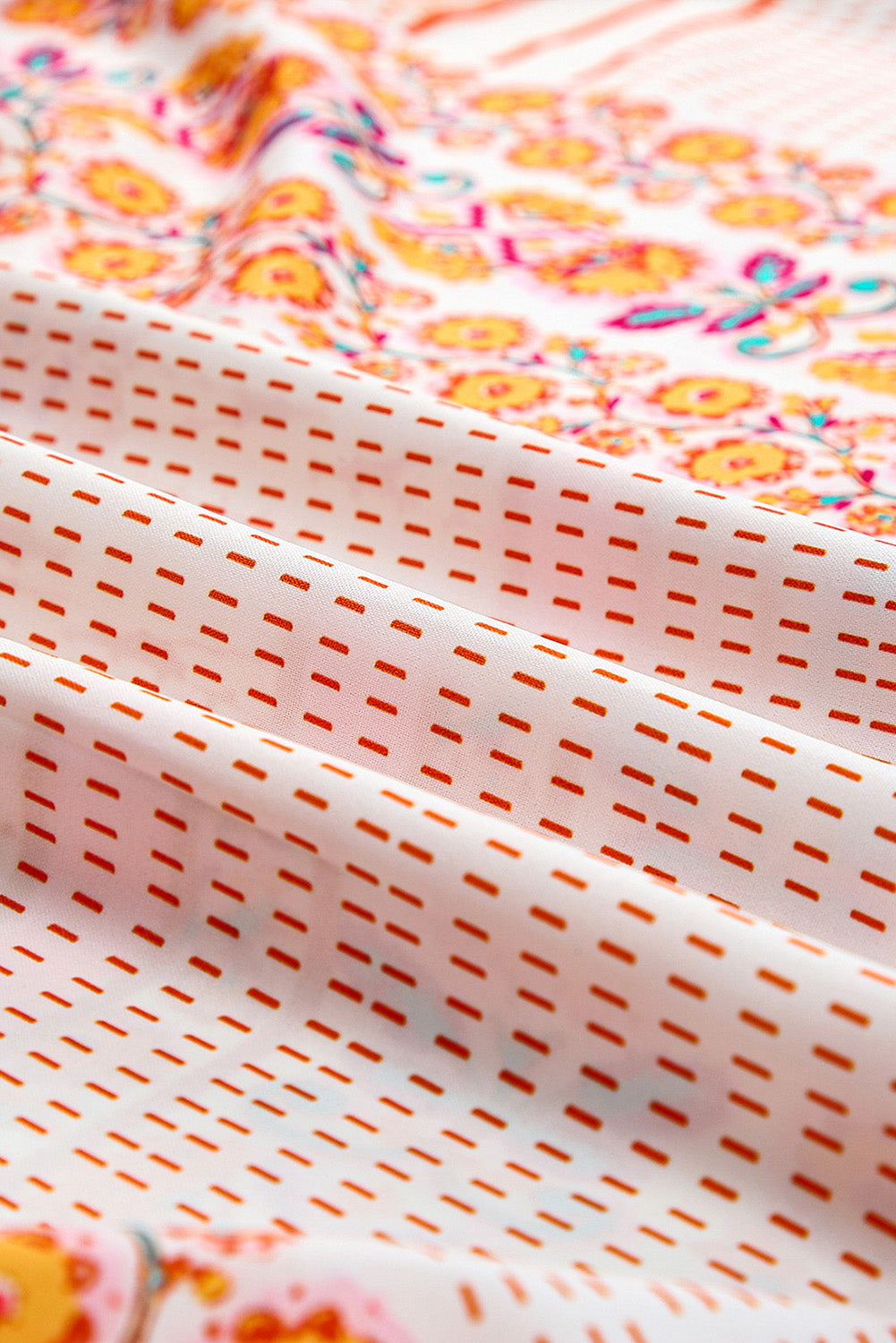 Patchwork fabric close-up with orange, teal, and pink motifs on white background